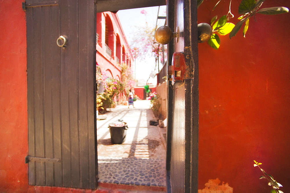 brown door is open showing nearby red colonial style buildings in Goree , Dakar, Senegal