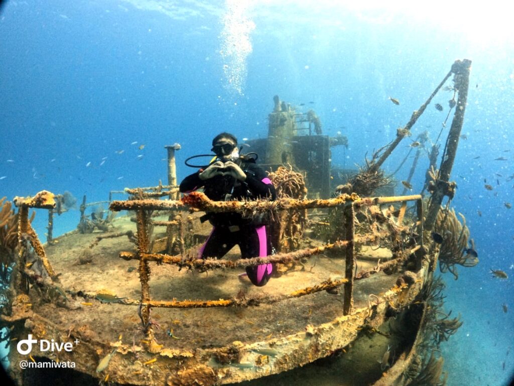 scuba diving in Nassau, Bahamas at a shipwreck. Diver is an African American woman throwing up a heart sign