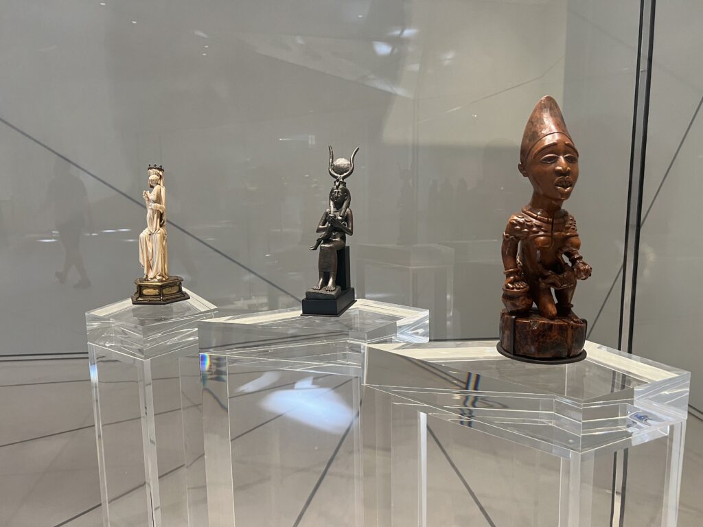 3 small statues of artifacts displaying a mother feeding her baby from 3 differnt periods of times and cultures