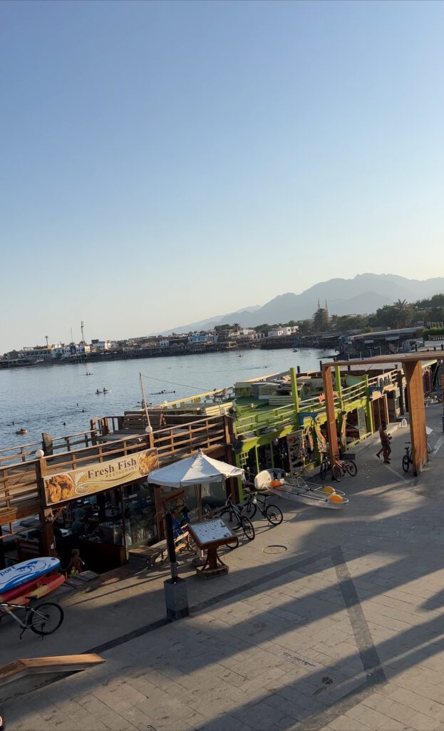 photo of Dahab boardwalk, behind is the sea with mountains in the background
