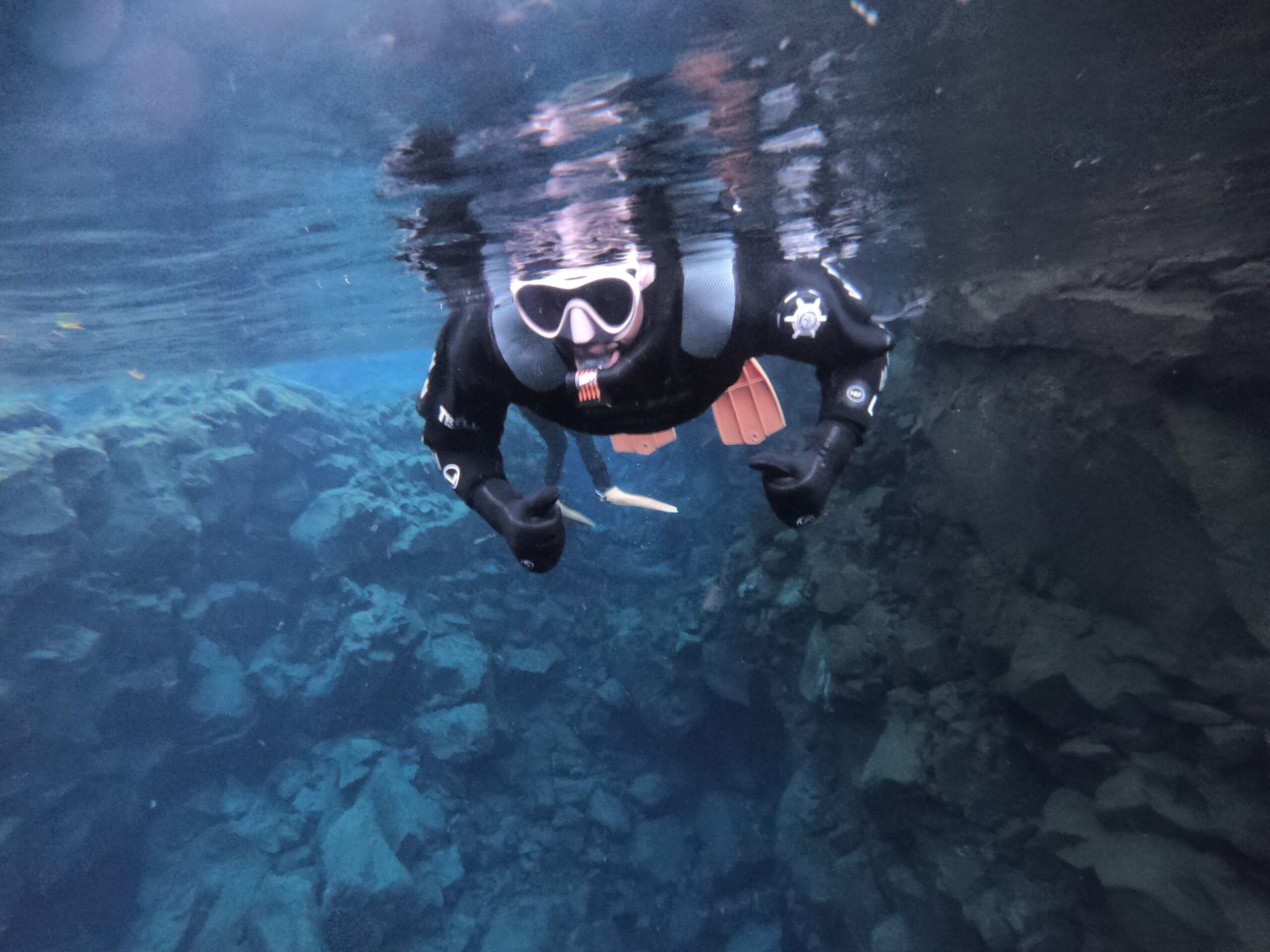 black woman is drysuit in Silfra Fissure in Iceland , woman is giving the thumbs up sign 