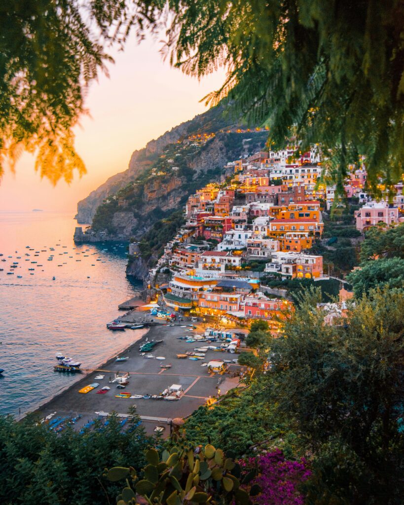 image of Amalfi coast at dusk with pink and yellow skies and lots of Italian coastal building