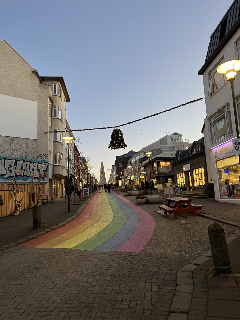 a street in Reykjavik with a rainbow painted on the street at dusk  