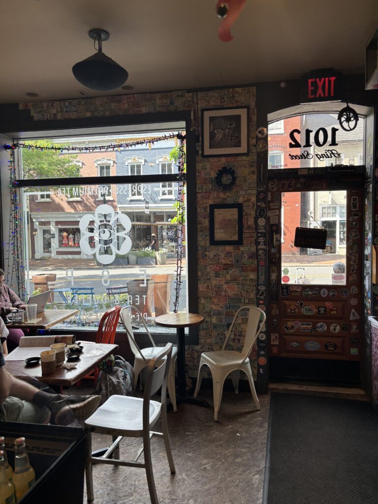 inside of ESP coffee shop showing chairs, window, and wall with lots of stickers and foreign money