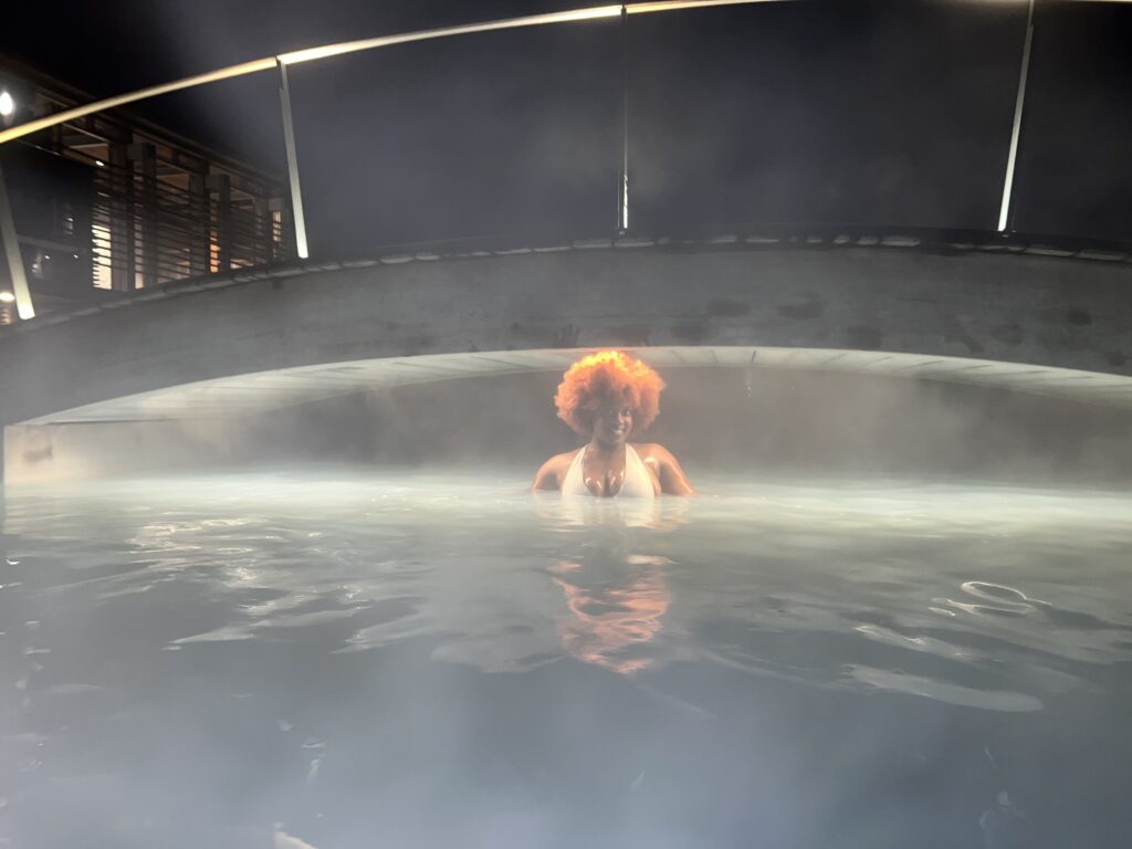 Black wman with ginger/orange afro standing in the Blue lagoon during the evening