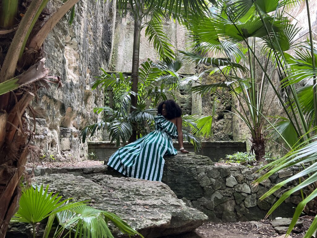 dark skinned woman in african fabric dress sitting on a limestone rock 