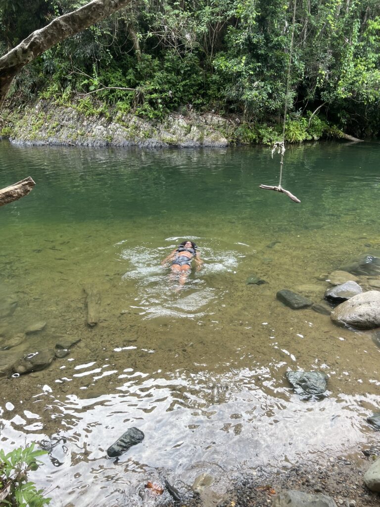 a black woman is floating in a river in El Yunque National Forest