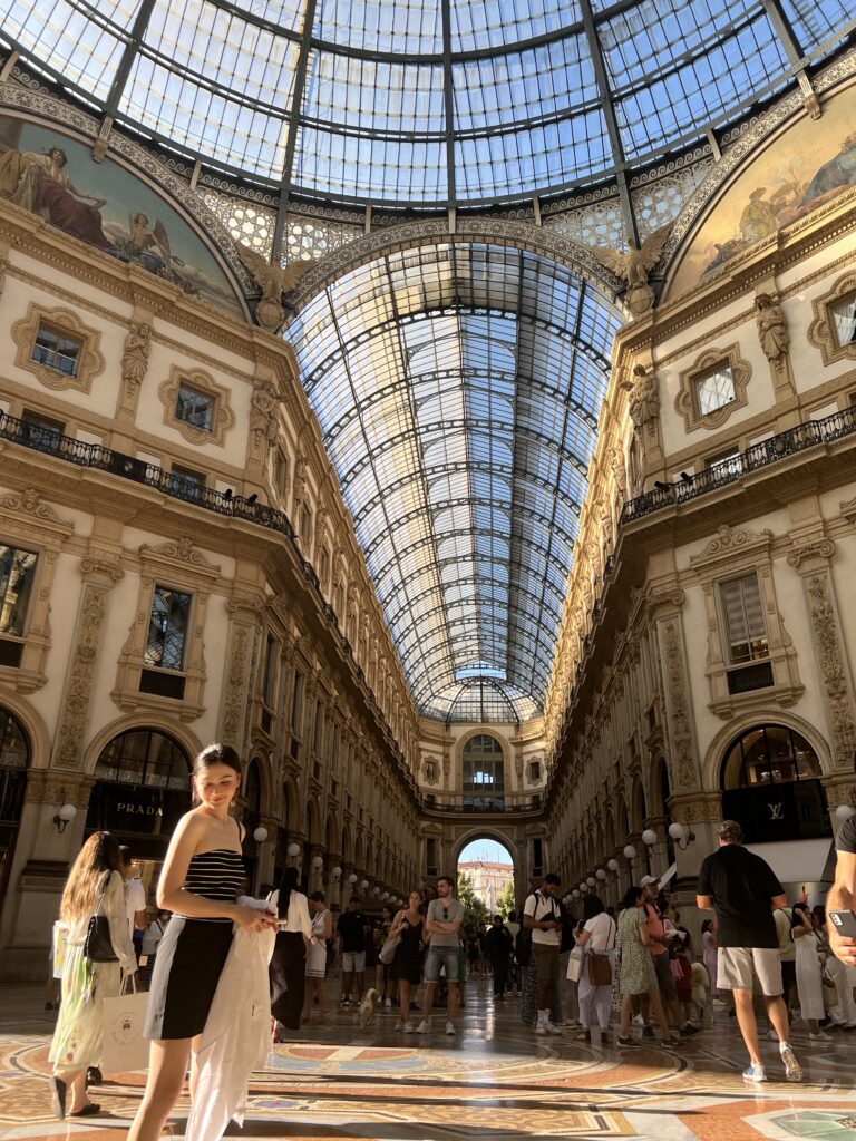 Tourists posing at Galleria Vittorio Emanuele II, a regal looking shopping center in Milan with gothic architecture and stunning glass ceilings 