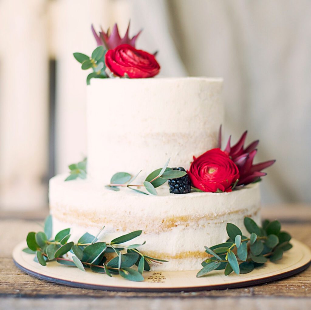 a classical white wedding cake with roses and green foliage
